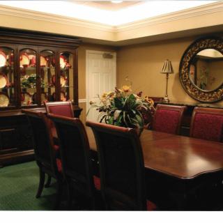 A sophisticated dining room with a large wooden table surrounded by chairs, featuring elegant decor and soft lighting.