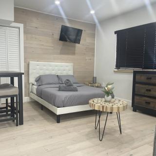 A modern and minimalist bedroom featuring a neatly made bed, a wall-mounted TV, and wooden furniture.