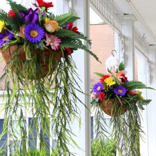 Colorful hanging flower baskets adorn a porch.