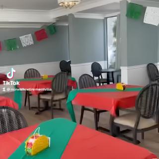A decorated restaurant with colorful tablecloths and festive flags hanging from the ceiling.