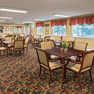 A well-lit dining area with tables, chairs, and decorative curtains.