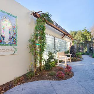 A well-maintained garden path with a bench and greenery alongside a building.