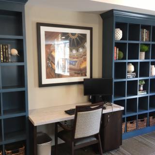 A home office setup with a desk, chair, computer, and bookshelves adorned with various decorations and books.