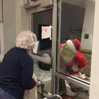 A joyful encounter between an elderly woman and Santa Claus outside a window, spreading holiday cheer.