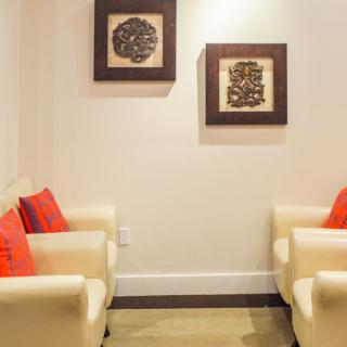 A cozy lounge area with cream-colored chairs and vibrant red cushions, adorned with framed artwork on the wall.