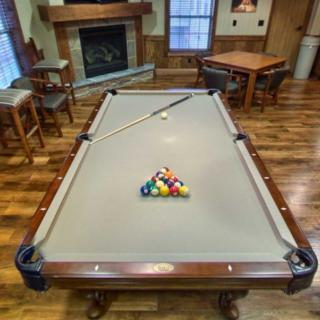 A cozy game room featuring a pool table with a cue stick and racked balls ready for play.