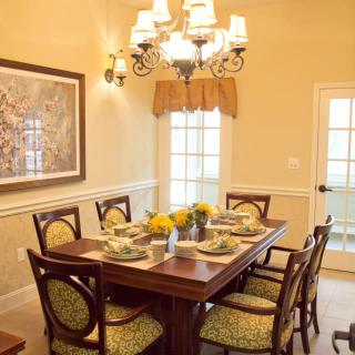 A cozy dining room with a wooden table set for six, featuring elegant decor and a chandelier.