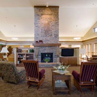 A cozy living room with a central stone fireplace, surrounded by comfortable seating and warm lighting.