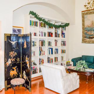 A cozy living room with a well-stocked bookshelf, decorative screen, and comfortable seating surrounded by elegant decor.