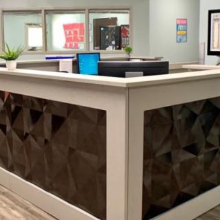 A modern reception area featuring a stylish desk with plants and computers.
