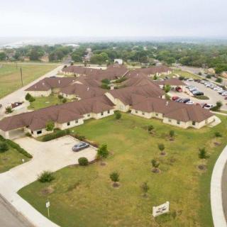 Aerial view of a residential complex with ample green spaces and parking areas.