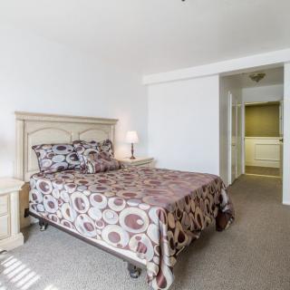 A cozy bedroom with a double bed, patterned bedspread, and adjacent bedside table with a lamp.