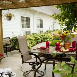 A cozy patio setup with a dining table surrounded by garden plants and flowers.