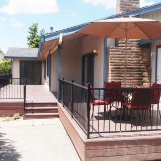 A spacious outdoor patio with a table, chairs, and an umbrella under a clear blue sky.