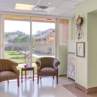 A bright and inviting waiting area in a healthcare facility, featuring comfortable armchairs and a view of the outdoors.