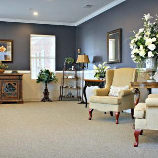 A well-decorated living room with armchairs, floral arrangements, and elegant furnishings.