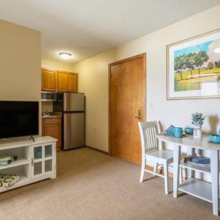 A cozy apartment living space featuring a compact kitchen, dining area, and television setup.