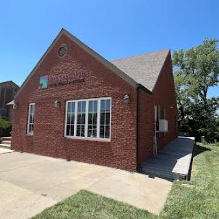 A modern brick building featuring large windows under a clear blue sky.