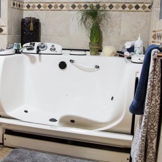 A modern bathroom featuring a large white bathtub adorned with various toiletries and surrounded by neatly hung towels.