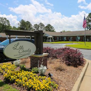 A welcoming entrance with vibrant flowers and a flag flying at a facility.
