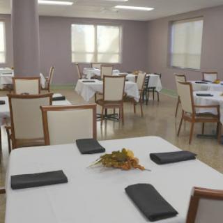 A spacious dining area set with white tablecloths and neatly arranged chairs, ready for guests.