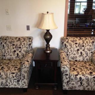 Two floral-patterned armchairs with a table and lamp in between, creating a cozy seating area.