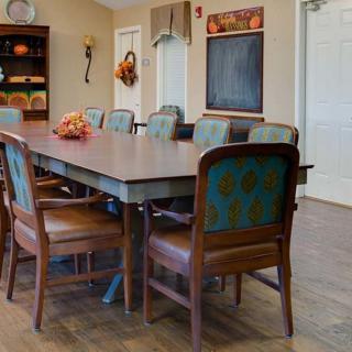 A spacious dining room with a large table surrounded by chairs, featuring warm and inviting decor.
