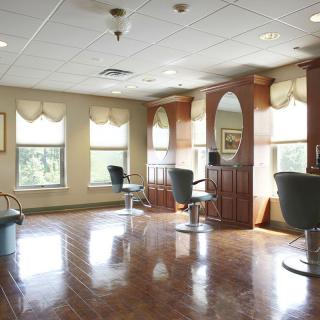 An empty hair salon with styling chairs and large mirrors by the windows.