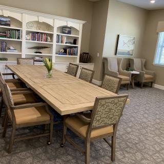 A well-appointed conference room featuring a large meeting table, surrounded by comfortable chairs, with a bookshelf in the background.