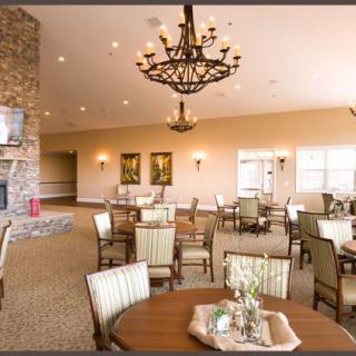 A spacious dining area featuring elegant chandeliers, comfortable seating, and a cozy fireplace.
