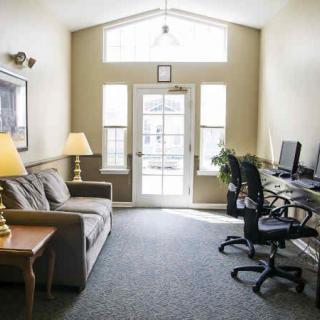 A cozy office space with computers and a sofa, illuminated by natural light from large windows.