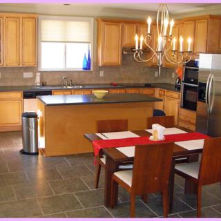 A modern kitchen with wooden cabinets, a center island, and a dining area featuring a chandelier.