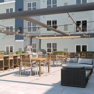 A modern outdoor patio with seating and string lights in an apartment complex.