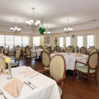 An elegant dining room with neatly arranged tables and chairs, decorated with chandeliers.