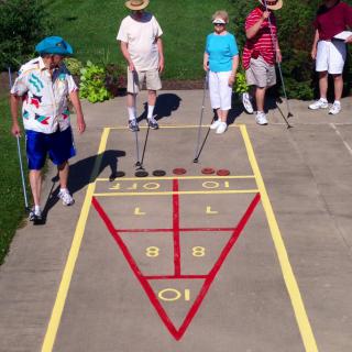 Seniors enjoying a game of shuffleboard outdoors.