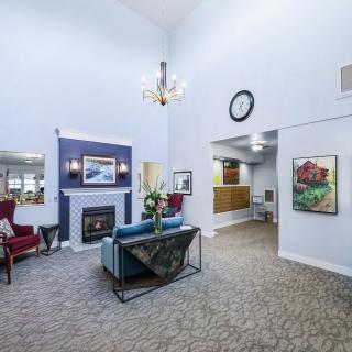 A spacious and elegantly decorated living room featuring a fireplace, chandelier, and comfortable seating.