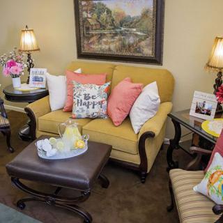 A cozy living room with a yellow sofa, colorful pillows, and elegant lamps.