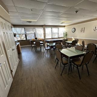A spacious and well-lit dining area featuring tables and chairs arranged for communal gatherings.