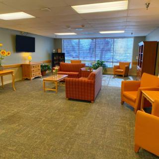 A modern lounge area with orange seating and large windows.