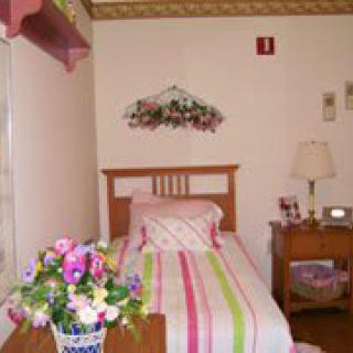 A cozy bedroom with a pastel-colored bedspread and floral decorations.