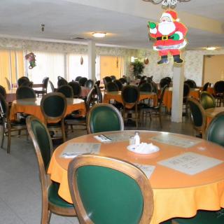 A restaurant dining area with orange tablecloths and holiday decorations.