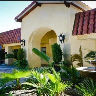 A Mediterranean-style house with a red-tiled roof and lush landscaping.