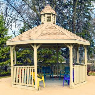 A wooden gazebo with colorful chairs in an outdoor setting.