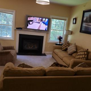 Cozy living room with a fireplace, sofas, and a wall-mounted TV.
