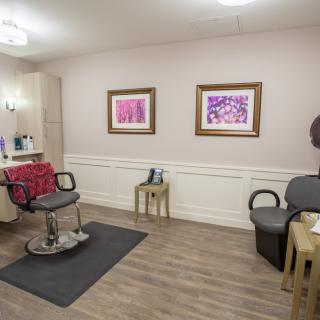 A well-appointed hair salon with styling chairs, artwork on the walls, and a cozy waiting area.