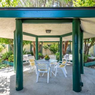 A serene outdoor pavilion surrounded by lush greenery, featuring a cozy seating arrangement.