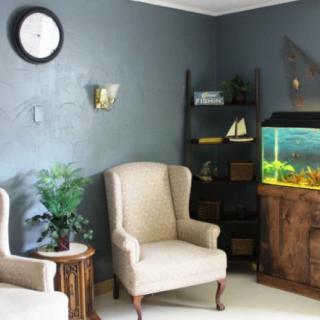 A cozy living room with armchairs, an aquarium, and stylish decor.