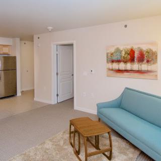 A modern living room with a blue sofa, wooden coffee table, and colorful artwork on the wall.