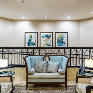 A cozy seating area in a lobby with a sofa, artwork, and ambient lighting.