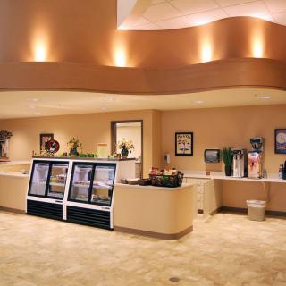A modern cafe interior featuring a beverage station and refrigerated display counters.